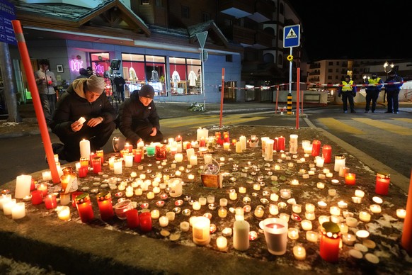 People lay candles near the Le Constellation bar, where a devastating fire left dead and injured during the New Year's celebrations in Crans-Montana, Swiss Alps, Switzerland, Thursday, Jan. 1, 20 ...