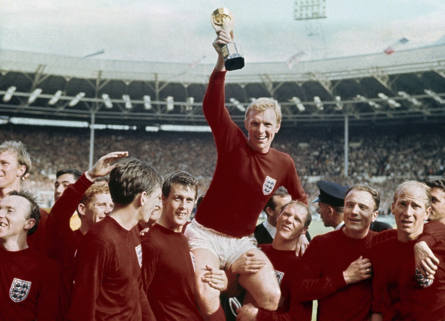 FILE - In this July 30, 1966 file photo, England&#039;s soccer captain Bobby Moore, center, is carried by teammates Geoff Hurst, center left, and Ray Wilson as he holds FIFA World Cup after England de ...