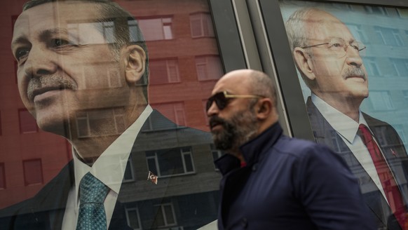 A man walks past election campaign billboards of Turkish President and People's Alliance's presidential candidate Recep Tayyip Erdogan, left, and CHP party leader and Nation Alliance's ...