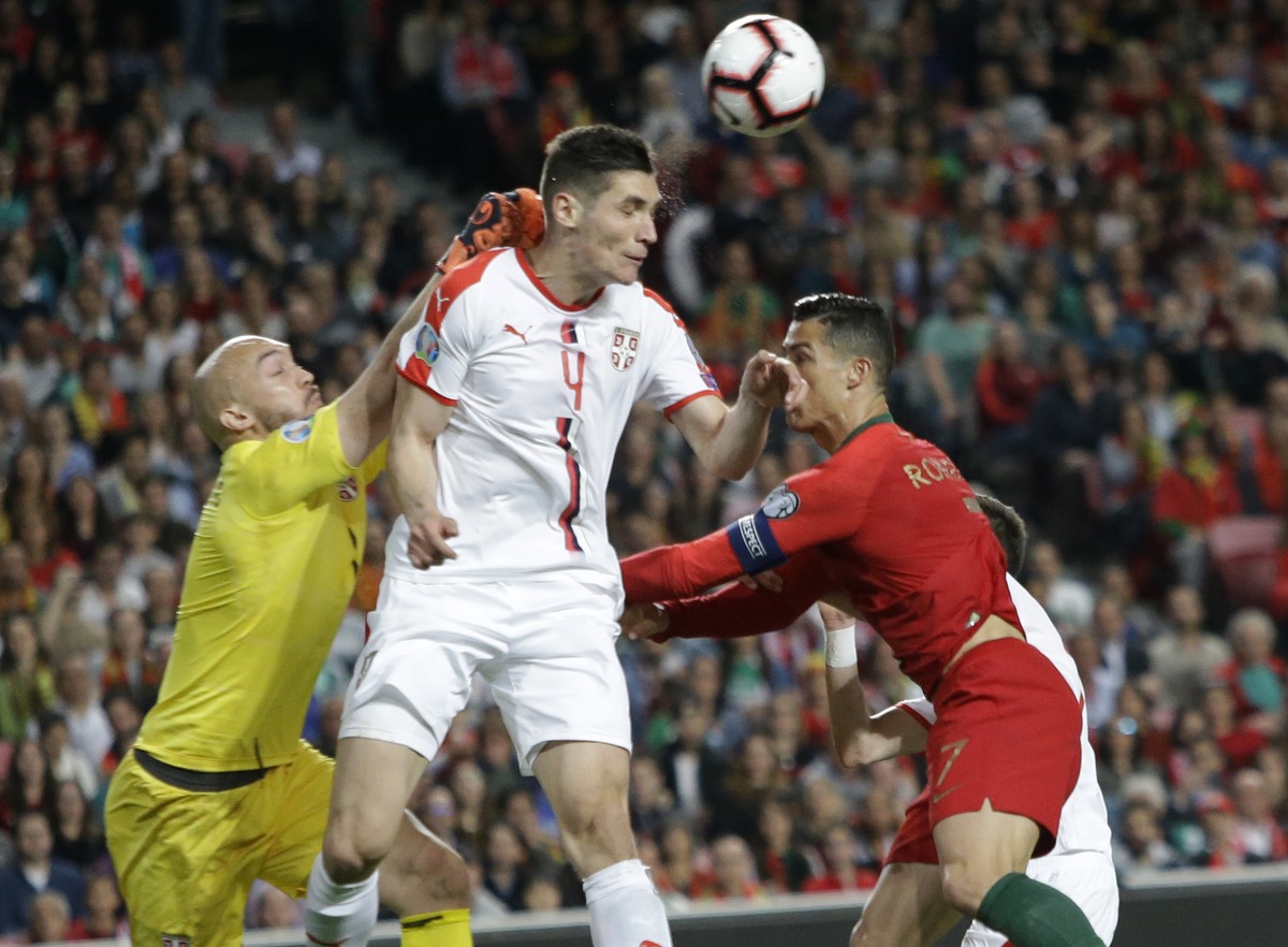 Serbia's goalkeeper Marko Dmitrovic, left, Serbia's Nikola Milenkovic, and Portugal's Cristiano Ronaldo challenge for the ball during the Euro 2020 group B qualifying soccer match betwe ...