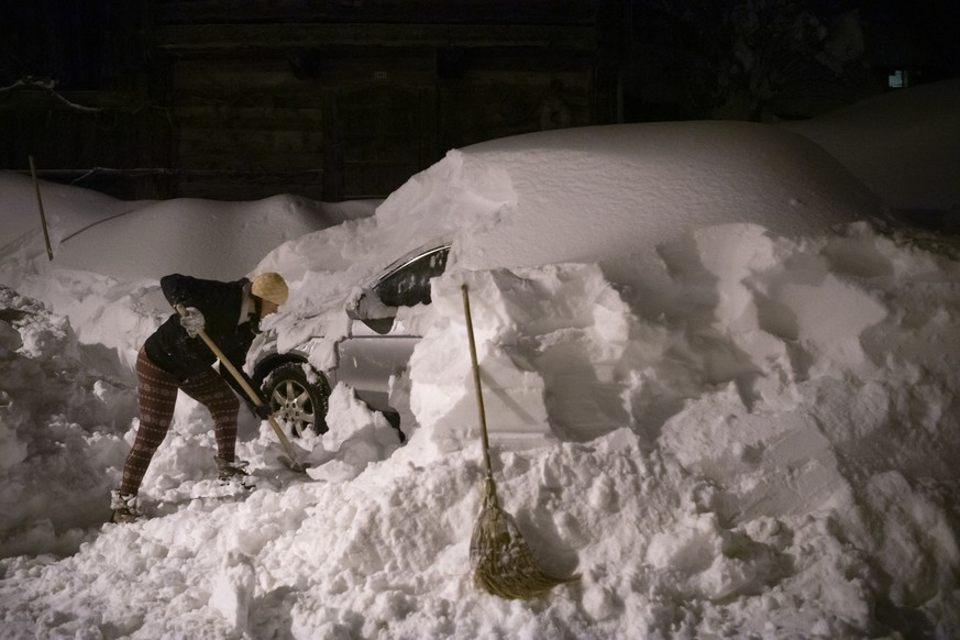 Eine Frau befreit ihr Auto vom Schnee nach den Rekordschneemengen der vergangenen Tage, am Sonntag, 17. Januar 2021, in Valens. (KEYSTONE/Gian Ehrenzeller)