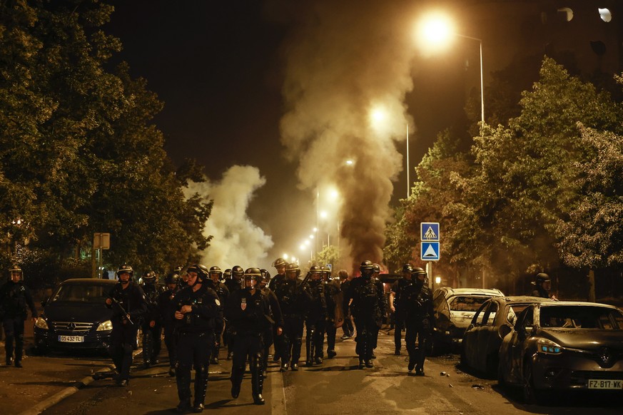 epa10716179 Riot police walk near burnt cars during clashes with protesters in Nanterre, near Paris, France, 29 June 2023. Violence broke out after police fatally shot a 17-year-old during a traffic s ...