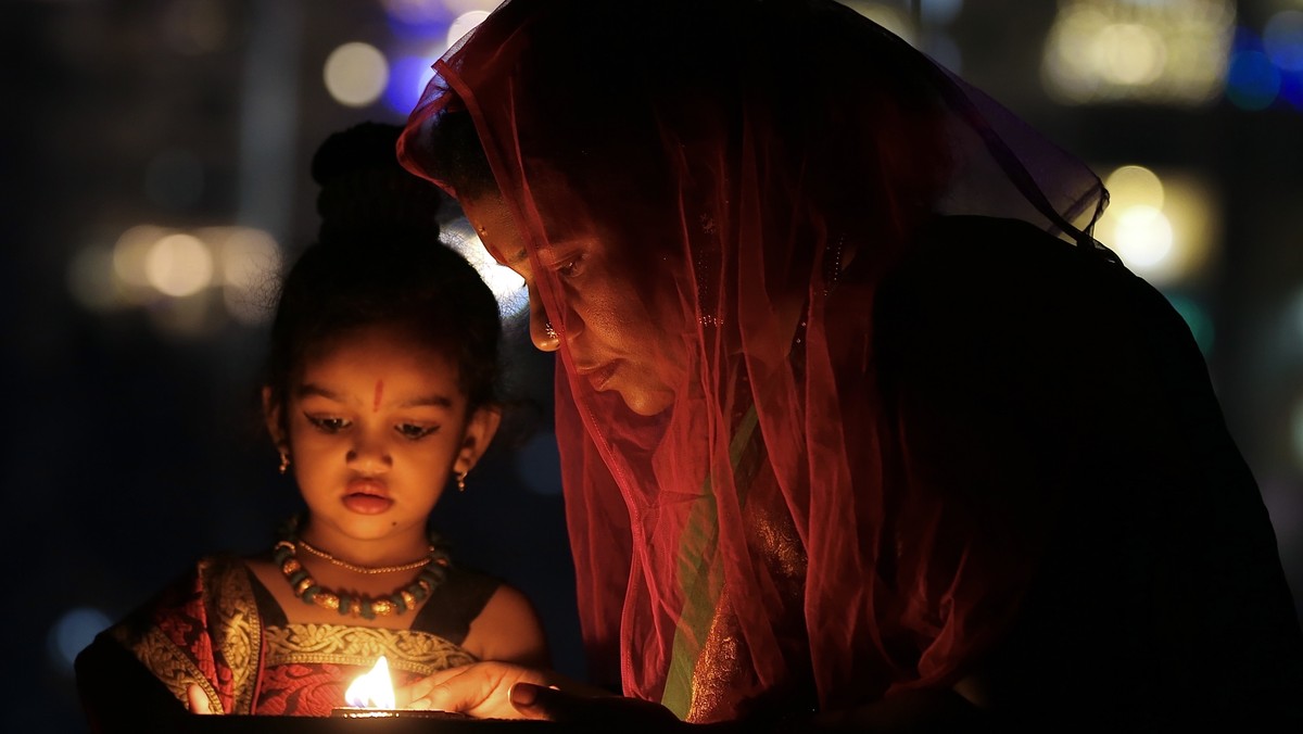 epa10263206 An Indian woman lights earthen oil lamps as part of Diwali, the Festival of Lights, in Bangalore, India, 24 October 2022. During Diwali, celebrating Kali, the Hindu Goddess of Ultimate Pow ...