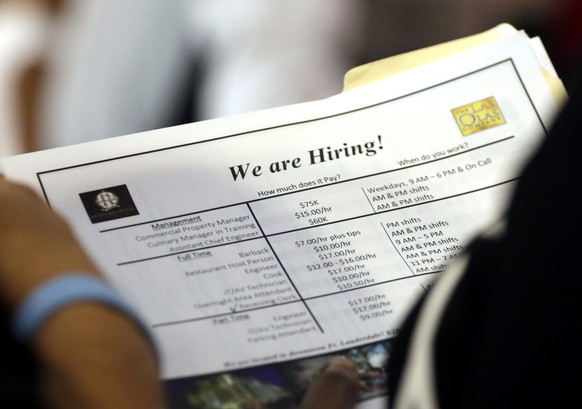 FILE-In this June 21, 2018 file photo, a job applicant looks at job listings for the Riverside Hotel at a job fair hosted by Job News South Florida, in Sunrise, Fla. The Labor Department is expected t ...