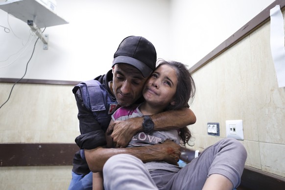 A Palestinian journalist comforts his niece wounded in an Israeli strike on her family home in Nusseirat refugee camp, in a hospital in Deir el-Balah, Gaza Strip, Sunday, Oct. 22, 2023. (AP Photo/Ali  ...