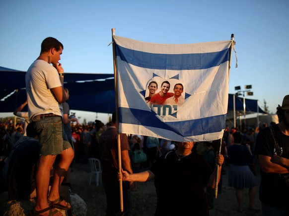 Israelische Flagge mit einem Bild der drei getöteten Teenager.