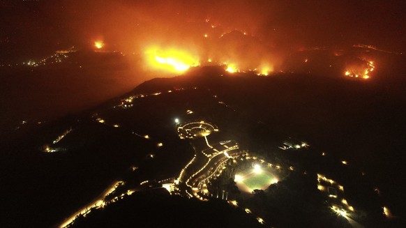 A wildfire approaches the Olympic Academy, foreground, in ancient Olympia, Wednesday, Aug. 4, 2021. Greece evacuated people in boats from an island beach Wednesday amid heavy smoke from a nearby wildf ...