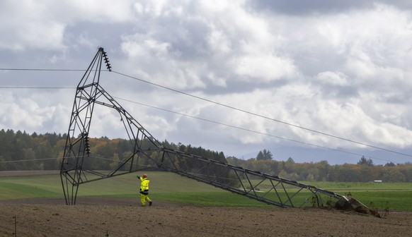 An employee of the Romande Energie company is work on an electricity pylon is seen on the ground after being knocked down by strong winds during the autumn storm, Benjamin, in Biere, Switzerland, Thur ...
