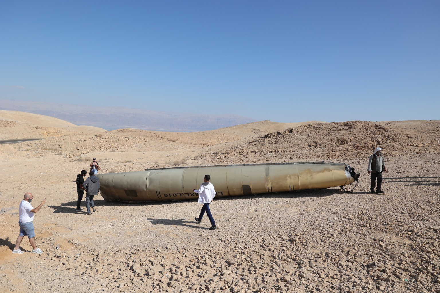 epa11637601 People look at the wreckage of an Iranian ballistic missile in the Negev desert near the Dead Sea, southern Israel, 02 October 2024. According to the Israeli military, Iran launched over 1 ...