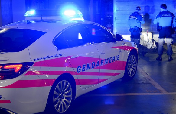 [Editor&#039;s note: photo mise-en-scene] A patrol of the cantonal police of Vaud searches a site, in the background, while their car with blue lights switched on is seen in the foreground, photograph ...