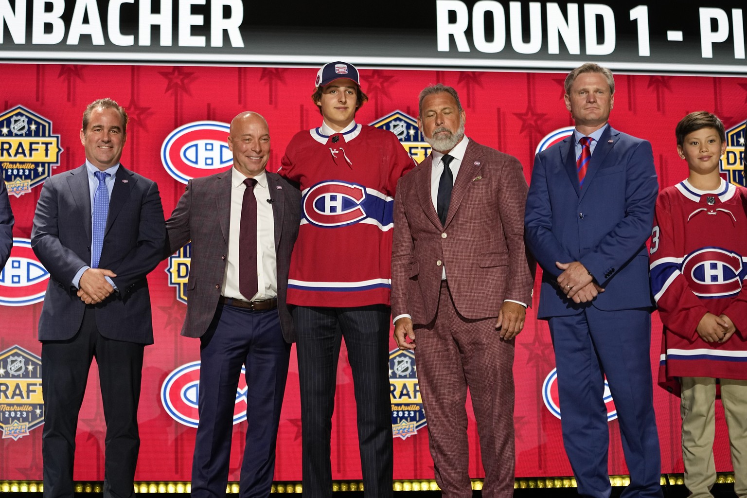 David Reinbacher, center, poses with Montreal Canadiens officials after being picked by the team during the first round of the NHL hockey draft Wednesday, June 28, 2023, in Nashville, Tenn. (AP Photo/ ...