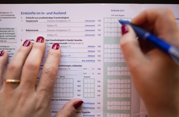 ARCHIVBILD ZUR ZUNAHME DER SELBSTANZEIGEN VON STEUERSUENDERN BEI DEN KANTONEN -- A married woman fills in details as to income made domestically and internationally in a Swiss tax return, photographed ...
