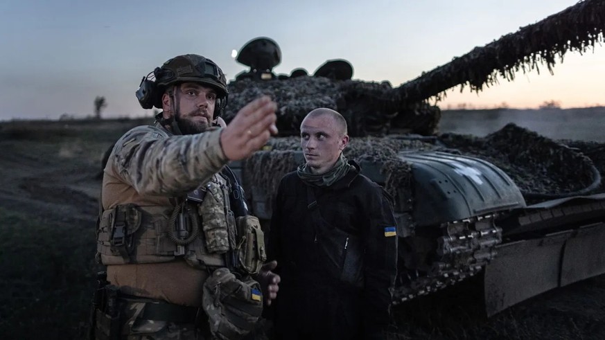 Die 22. Brigade der Ukraine: Ein kommandierender Soldat gibt bei einer Nachtschießübung vor einem T-72 Panzer Anweisungen.