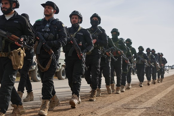 Syria's Interior Ministry forces march as a convoy passes through en route to the mostly Kurdish town of Qamishli, where the forces are deploying under a ceasefire agreement with the Kurdish-led  ...