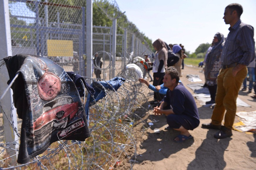 epa05332603 Migrants stand by the border fence in a makeshift camp near the Horgos border crossing into Hungary, near Horgos, Serbia, 27 May 2016. Several hundred migrants wanting to enter Hungary are ...