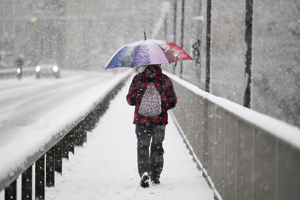 Ein Mann laeuft mit seinem Regenschirm im Schnee ueber die Kirchenfeldbruecke, am Donnerstag, 30. November 2023 in Bern. In mehreren Regionen der Schweiz kam es zu Schneef