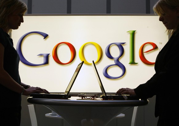 FILE- In this April 17, 2007 file photo, exhibitors of the Google company work on laptop computers in front of an illuminated sign of the Google logo at the industrial fair Hannover Messe in Hanover,  ...