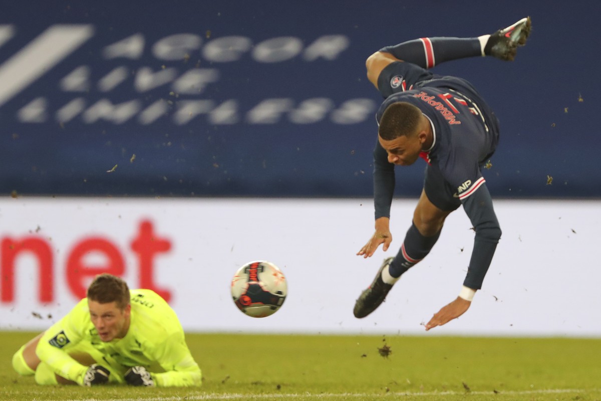 PSG's Kylian Mbappe, right, jumps over Montpellier's goalkeeper Jonas Omlin during the French League One soccer match between Paris Saint-Germain and Montpellier at the Parc des Princes stad ...
