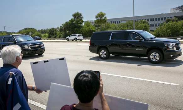 Two vehicles in former President Donald Trump&#039;s motorcade head towards the entrance to the airport past supporters flashing signs in support of the former president in West Palm Beach, Fla., on M ...