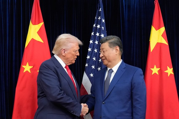 FILE - President Donald Trump, left, and Chinese President Xi Jinping, right, shake hands before their meeting at Gimhae International Airport in Busan, South Korea, Oct. 30, 2025. (AP Photo/Mark Schi ...
