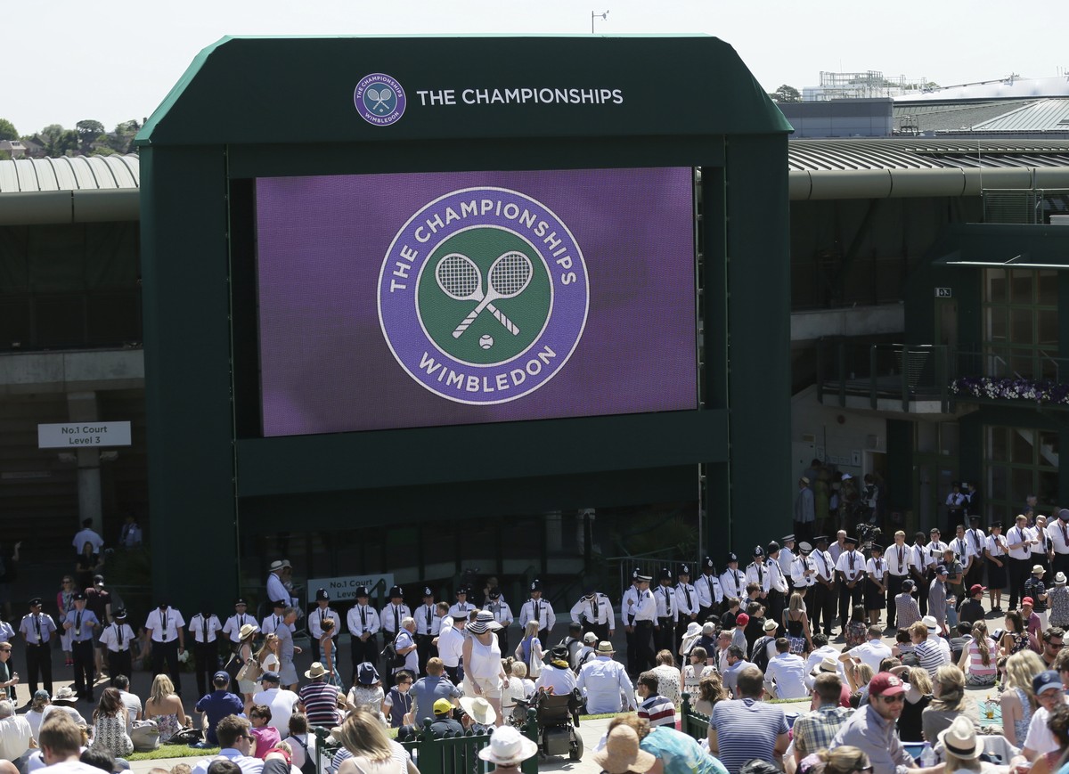 FILE - British police officers line up under the big screen on Murray Mount, ahead of the minute silence for the victims of the shooting in Tunisia last week, at the All England Lawn Tennis Championsh ...