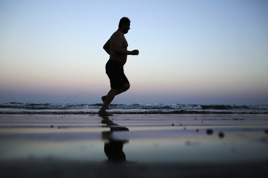 In this Feb. 13, 2018 photo, a man jogs on the beach after the sun sets in Aden, Yemen. Violence, famine and disease have ravished the country of some 28 million, which was already the Arab world’s po ...