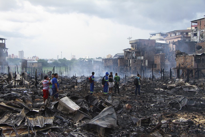 Residents stand in the scorched remains of the Educandos neighborhood in Manaus, Brazil, Tuesday, Dec. 18, 2018. Officials say the fire engulfed the neighborhood in the northern Brazilian city of Mana ...