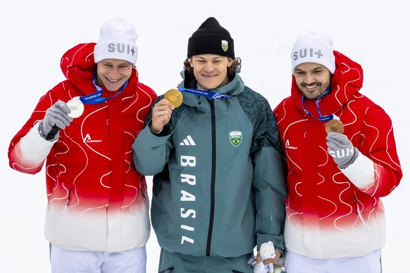 Gold medalist Brazil's Lucas Pinheiro Braathen, centre, Silver medalist Switzerland's Marco Odermatt, left, and bronze medalist Switzerland's Loic Meillard, right, walk to on the podium ...