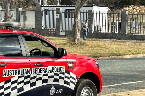 FILE - A man walks along a fence that surrounds a a building on the grounds of a proposed new Russian embassy near the Australian Parliament in Canberra where an Australian Federal Police officer obse ...