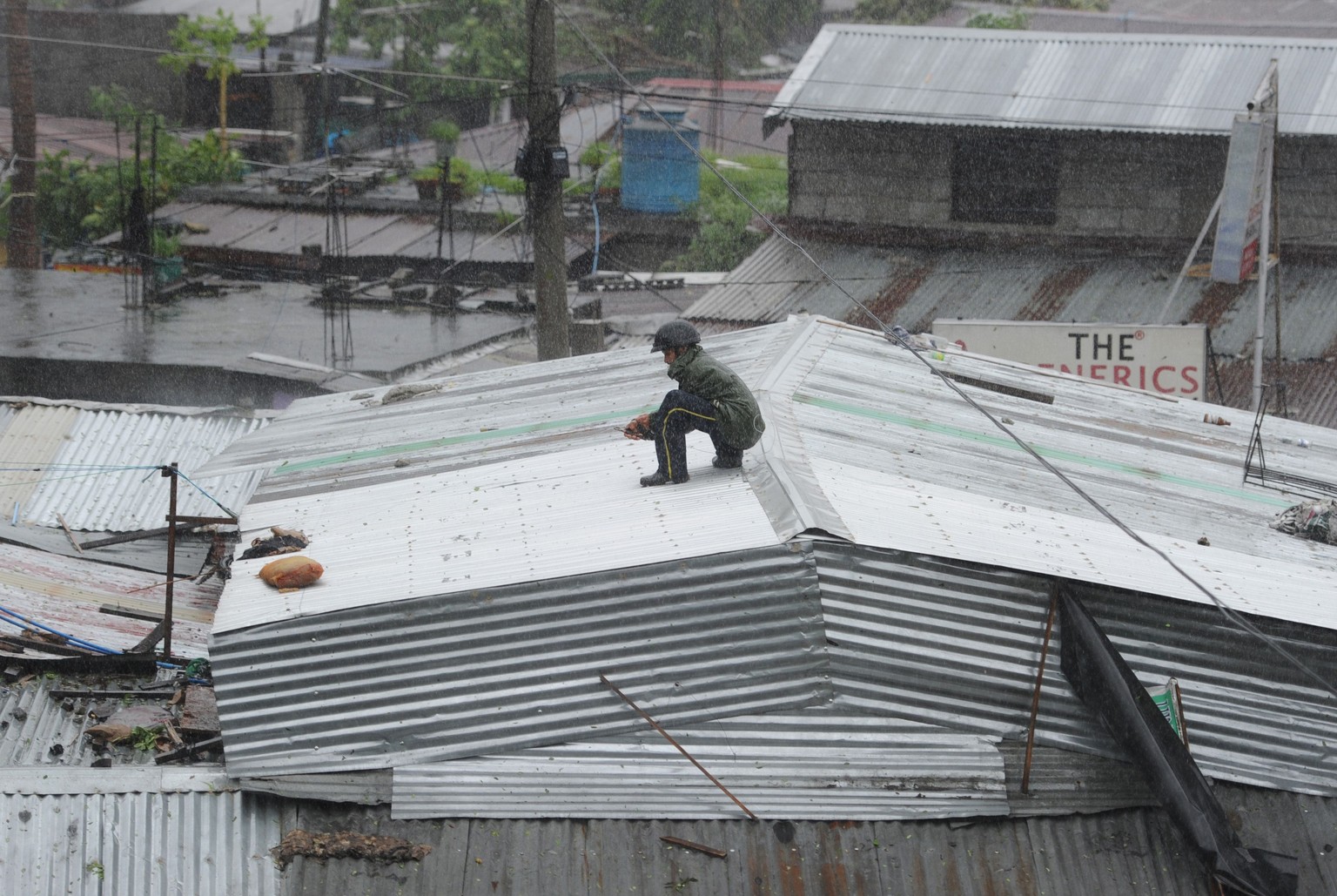 Ein Bewohner von Manila befestigt und flickt das Dach seines Hauses.