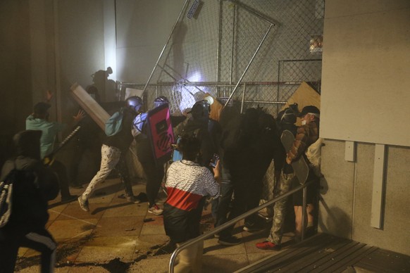 Protesters react during a demonstration, Friday, July 17, 2020 in Portland, Ore. Militarized federal agents deployed by the president to Portland, Oregon, fired tear gas against protesters again overn ...