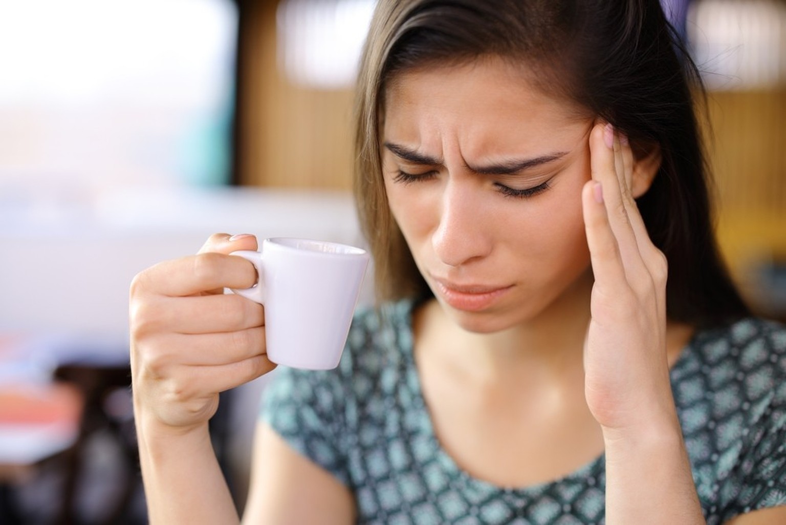 Frau mit Kaffee, Kopfschmerzen (Symbolbild)