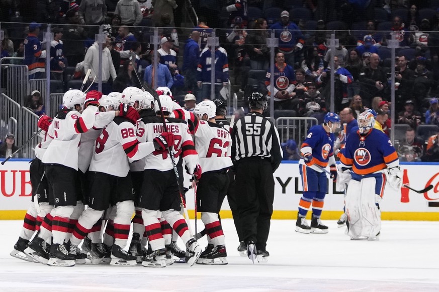 New York Islanders&#039; Ryan Pulock (6) comforts goaltender Ilya Sorokin (30) as the New Jersey Devils celebrate the winning goal after the overtime period of an NHL hockey game Friday, Oct. 20, 2023 ...