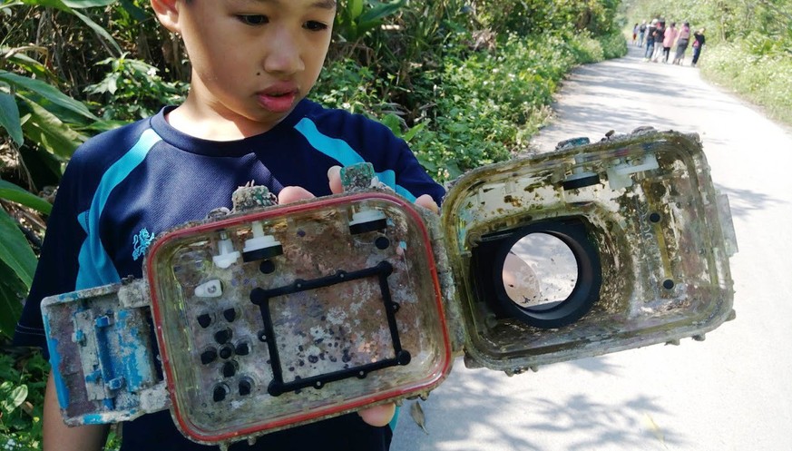 epa06635674 A handout photo made available by teacher Park Lee on 29 March 2018 shows a school pulpil displaying a barnacle-covered water-proof camera casing which washed up on a beach in Ilan County, ...