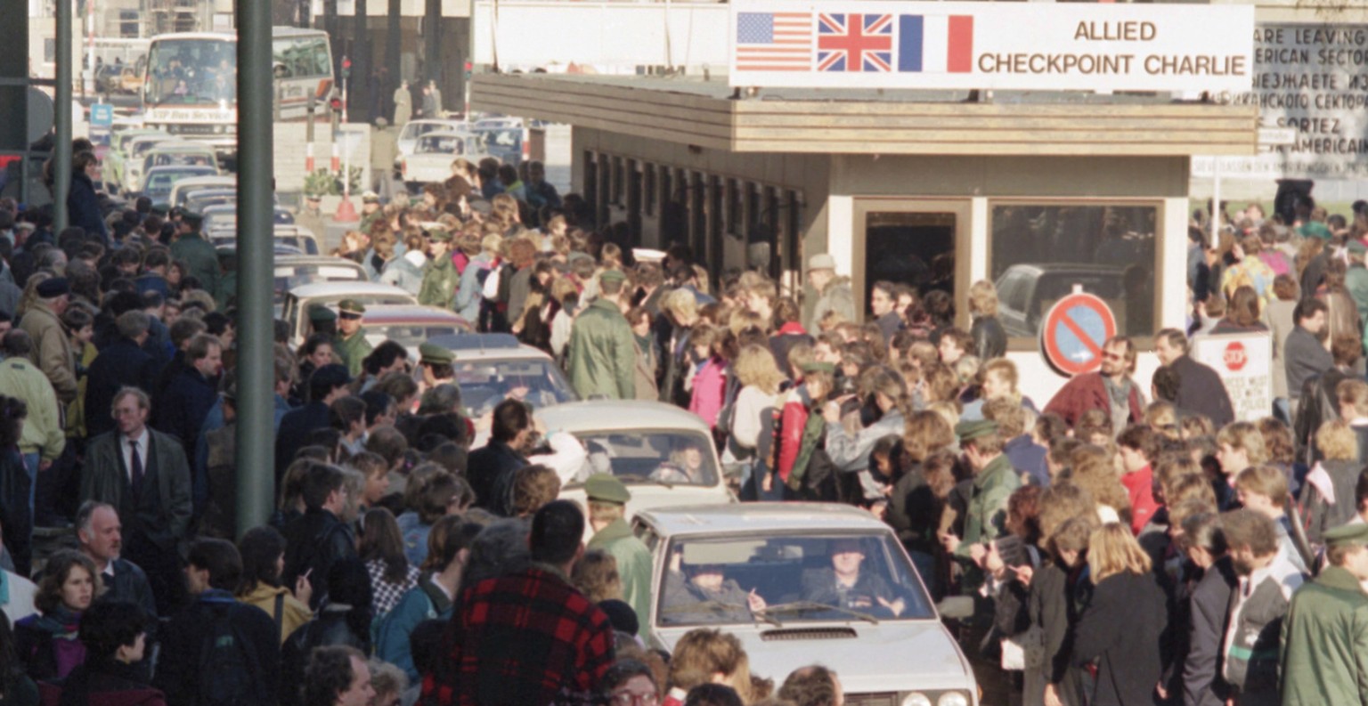 East German citizens are applauded by West Berliners when they cross Checkpoint Charlie with their cars to visit West Berlin, Nov. 10, 1989. Thousands of East Germans moved into West Berlin after the  ...