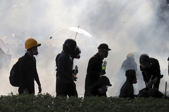 FILE - In this Sunday, Nov. 17, 2019, file photo, pro-democracy protestors react as police fire tear gas at Hong Kong Polytechnic University in Hong Kong. By day, the small commercial kitchen in a Hon ...