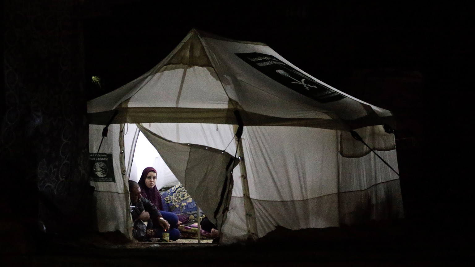 epa11068201 A Palestinian woman, who fled with her family from the northern Gaza Strip, sits inside a makeshift tent, in the west of the city of Deir al-Balah, central Gaza Strip, 10 January 2024. Mor ...