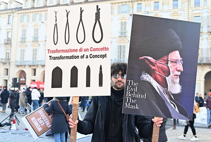 epa10370521 A protester holds signs during a demonstration against the Iranian regime organized by the Iranian community, in Turin, Italy, December 17, 2022, following Iran's death sentence and public...