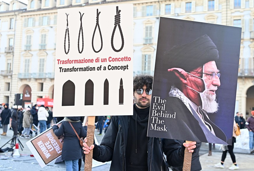 epa10370521 A protester holds placards during a demonstration against Iran&#039;s regime staged by the Iranian community, in Turin, Italy, 17 December 2022, following Iran&#039;s sentencing to death a ...