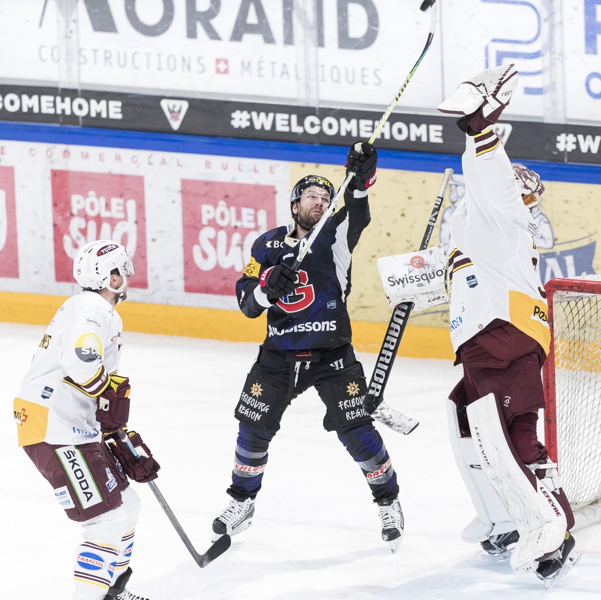L'attaquant fribourgeois David Desharnais, centre, lutte pour le puck avec le gardien genevois Gauthier Descloux, droite, lors du match du championnat suisse de hockey sur glace de National Leagu ...