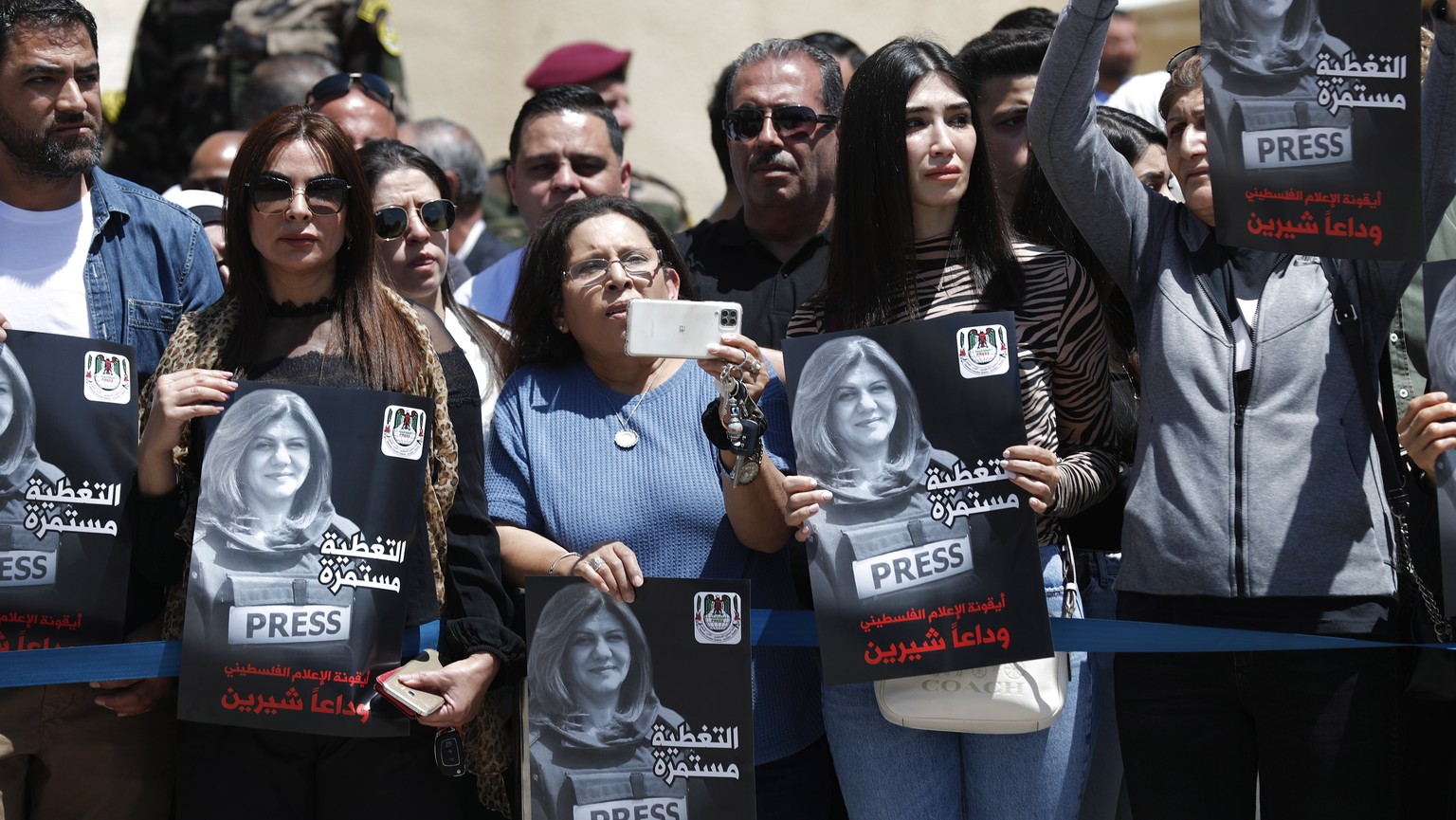 Frauen tragen an der offiziellen Trauerfeier in Ramallah (Westjordanland) Plakate mit einem Bild von Scherin Abu Akleh. 