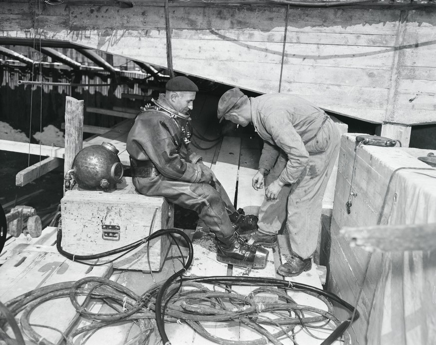 1950: Umbau Bahnhofbrücke Zürich: Arbeiter und Mann in altem Taucheranzug.