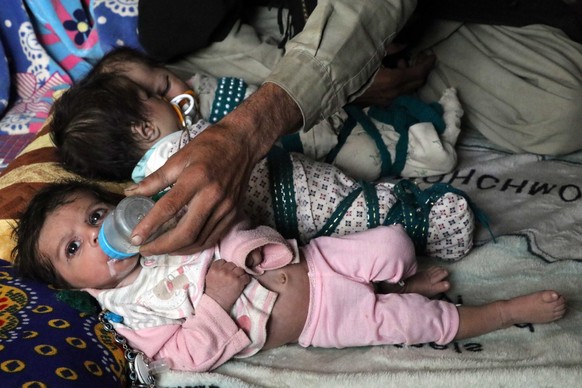 epa09625457 Ehsanullah, a father or newborn triplets sons sit next to his babies at his home in Kandahar, Afghanistan, 06 December 2021. Ehsanullahl said he was grateful to Allah for blessing him with ...