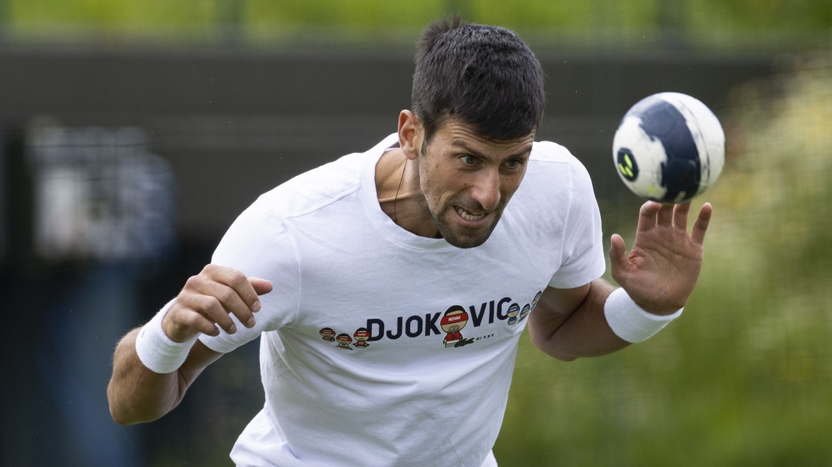 epa09322429 Novak Djokovic of Serbia plays with a small football during a practice session at the Aorangi Practice Courts at The Wimbledon Championships tennis tournament in Wimbledon, Britain, 04 Jul ...