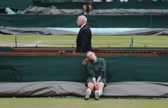 A female court coverer sits and waits for the signal to cover the court as showers skirt around Wimbledon on women&#039;s final day at the All England Lawn Tennis Championships at Wimbledon, London, S ...
