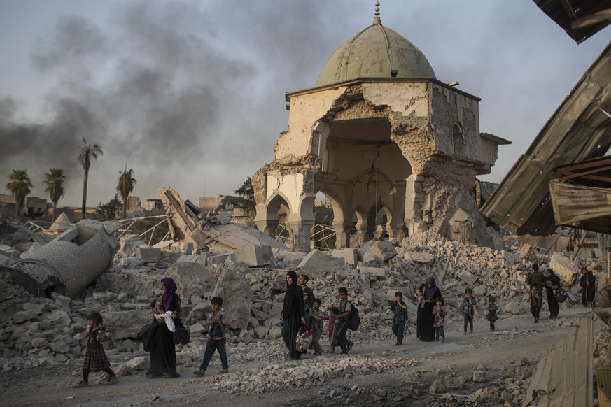 FILE - In this July 4, 2017, file photo, fleeing Iraqi civilians walk past the heavily damaged al-Nuri mosque as Iraqi forces continue their advance against Islamic State militants in Iraq&#039;s Old  ...