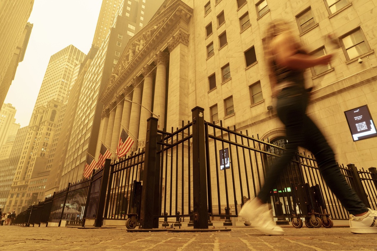 A pedestrian walks past the smoke and haze shrouded New York Stock Exchange building in New York City Wednesday, June 7, 2023. Intense Canadian wildfires are blanketing the northeastern U.S. in a haze ...