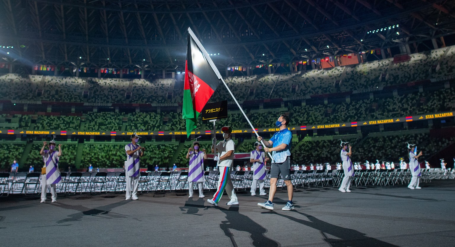 epa09427332 A Paralympic Volunteer carries the national flag of Afghanistan during the Athletes&#039; Parade in the Opening Ceremony for the Tokyo 2020 Paralympic Games, Tokyo, Japan, 24 August 2021.  ...