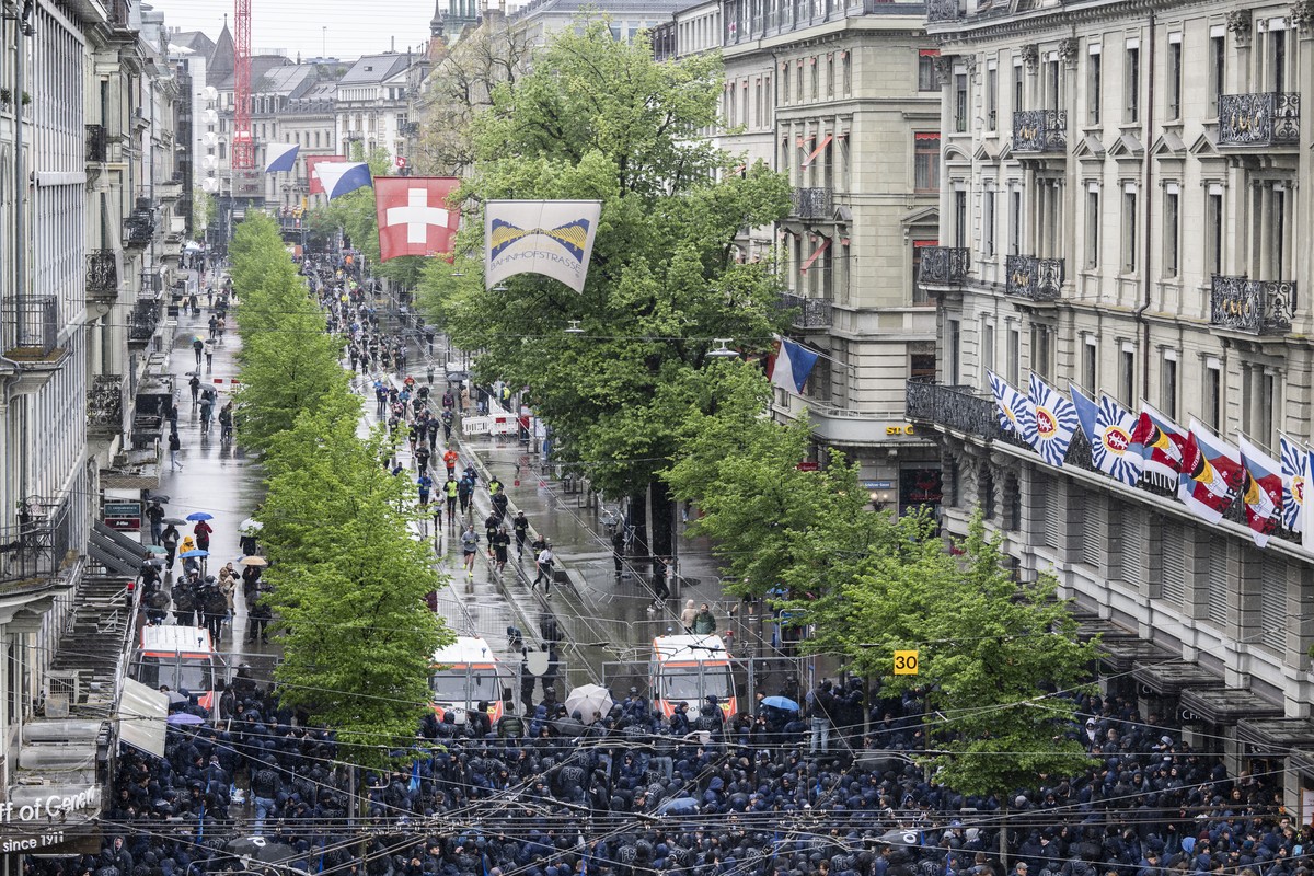 Polizisten schuetzen die Laeufer vor dle FCZ Fans an der Bahnhofstrasse am den 21. Zuercher Marathon ein, aufgenommen am Sonntag, 21. April 2024 in Zuerich. (KEYSTONE/Ennio Leanza)