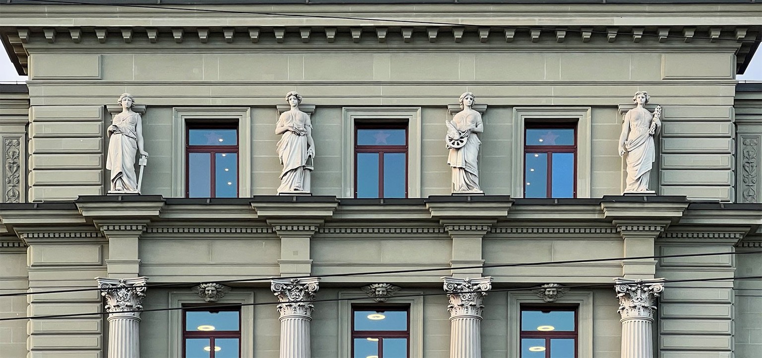 Gotthardgebäude in Luzern, vier Frauen als Symbolträgerinnen, erkennbar an ihren Attributen: die Ingenieurtechnik stützt sich auf den Rechenschieber, die Architektur führt einen Zirkel mit sich, die M ...